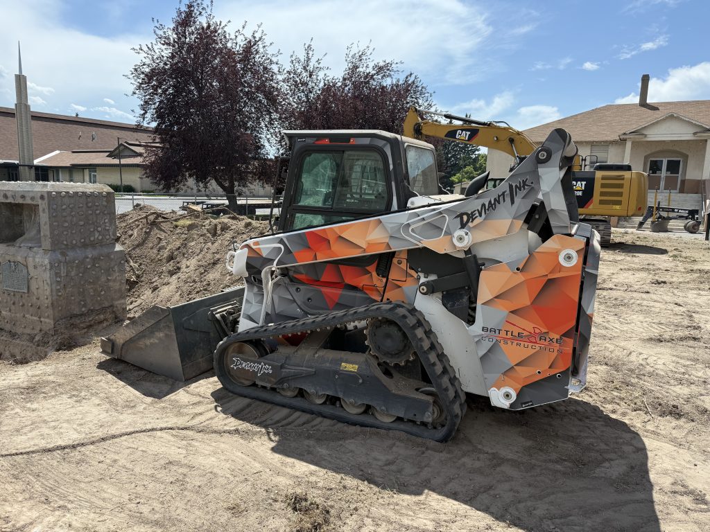 Custom Bobcat skid steer wrap in angular orange, grey, and red design for Battle Axe Construction by Deviant Ink